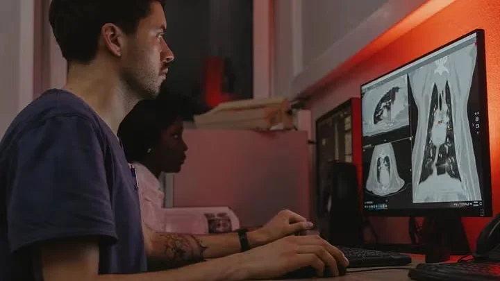 Man and woman reviewing medical scans on dual monitors.