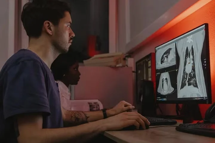 Man and woman reviewing medical scans on dual monitors.