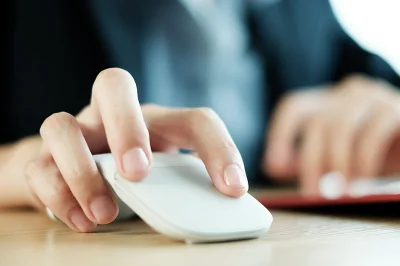 Close-up of a person using a white computer mouse.