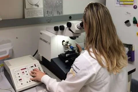 Scientist using a Leica ultramicrotome to prepare ultrathin biological samples for electron microscopy in a laboratory setting.